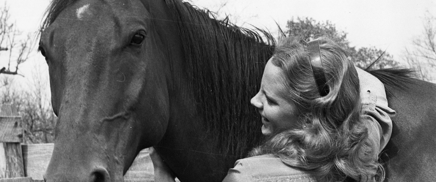 Reba with arms wrapped around horse